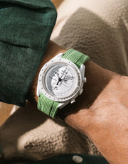 Mint rubber strap fitted to an OMEGA x Swatch MoonSwatch Mission to the Moonphase watch, worn on the wrist in a lifestyle shot with clothing visible