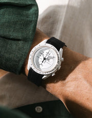 Smooth black rubber strap fitted to an OMEGA x Swatch MoonSwatch Mission to the Moonphase watch, worn on the wrist in a lifestyle shot with clothing visible