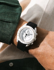 Vertech black rubber strap fitted to an OMEGA x Swatch MoonSwatch Mission to the Moonphase watch, worn on the wrist in a lifestyle shot with clothing visible